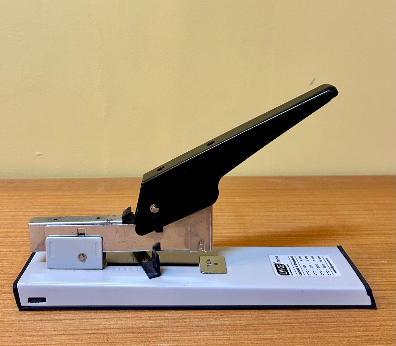 Grampeador de mesa com a parte metálica na cor preta e base na cor branca