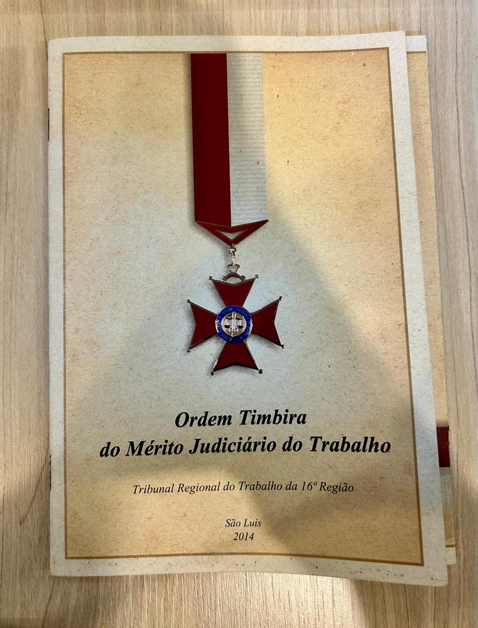 Revista na cor branca e com a medalha vermelha na capa como ilustração