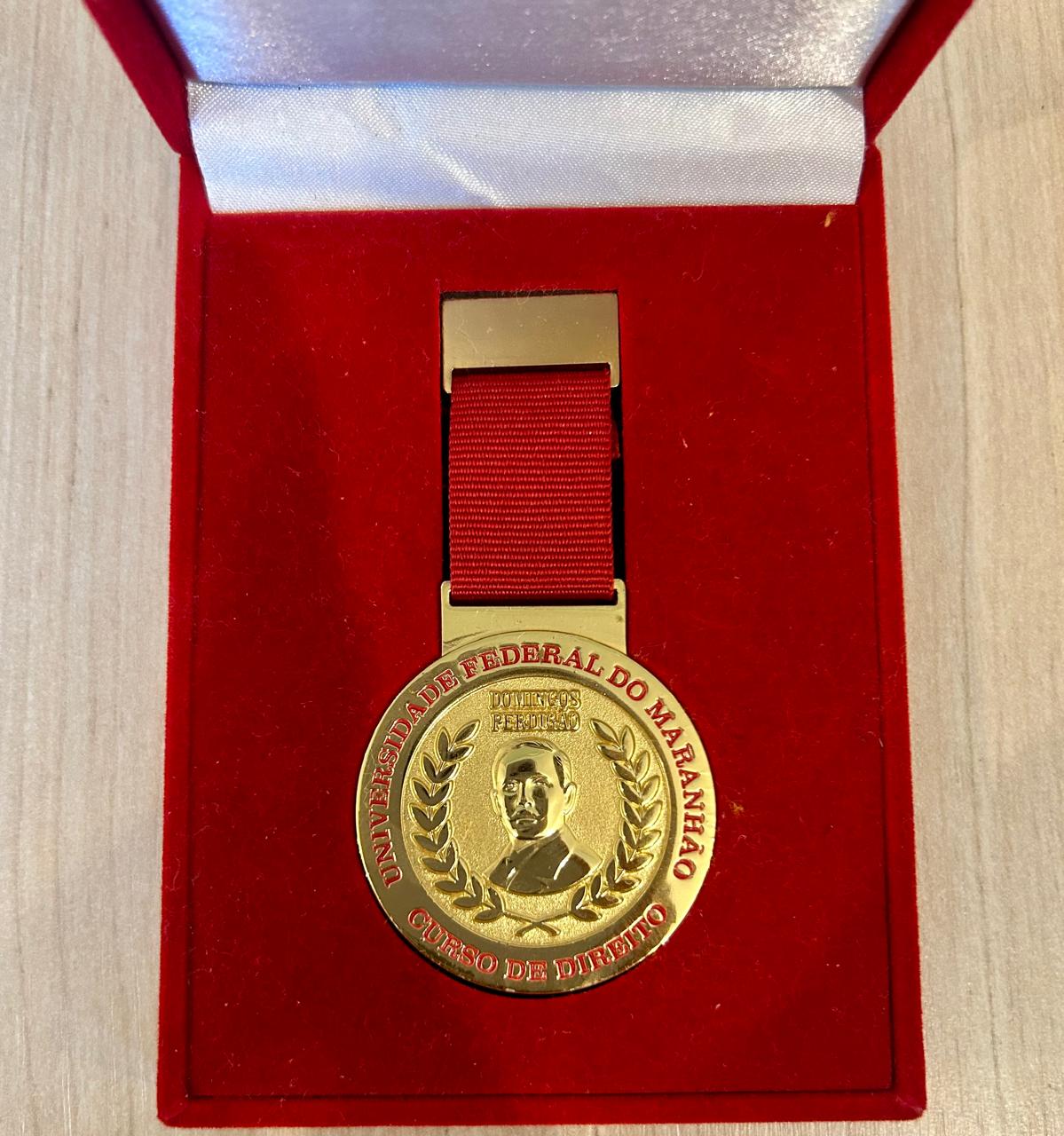 Medalha na cor dourada apoiada em base na cor vermelha