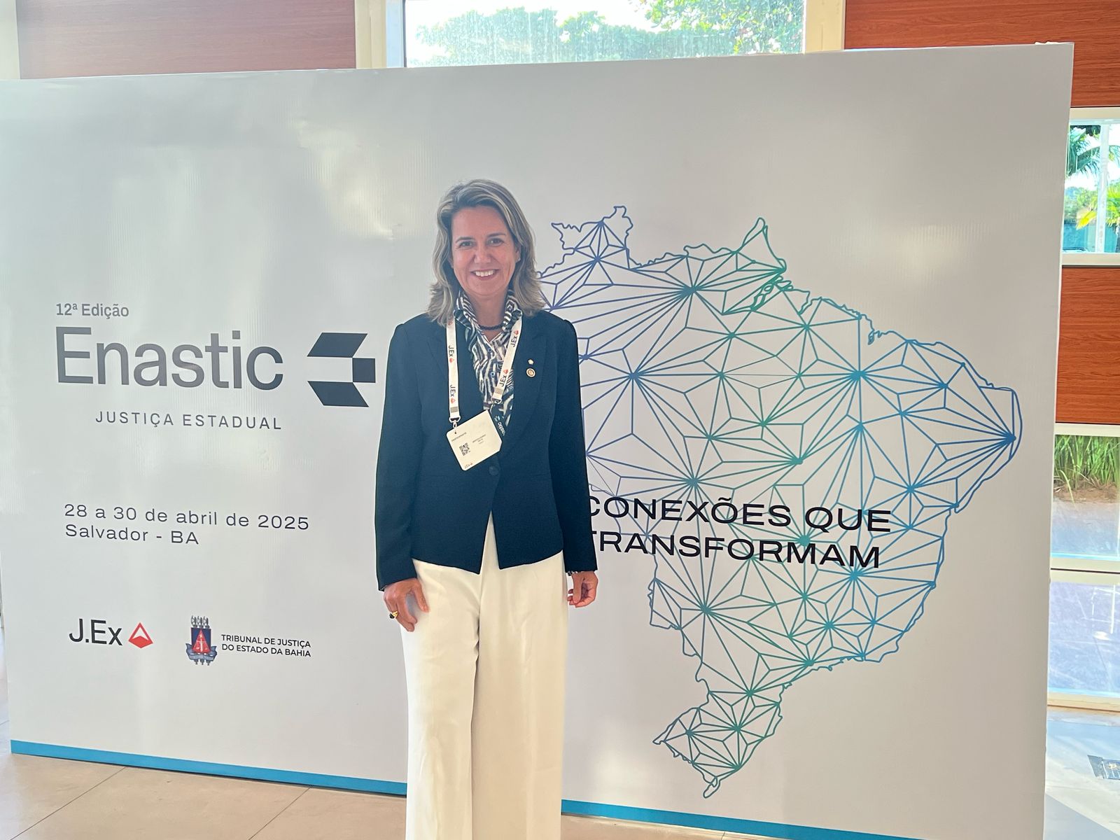 Foto mostra a presidente do TRT-16 desa. Márcia Andrea Farias da Silva posicionada diante de um painel do ENASTIC. 