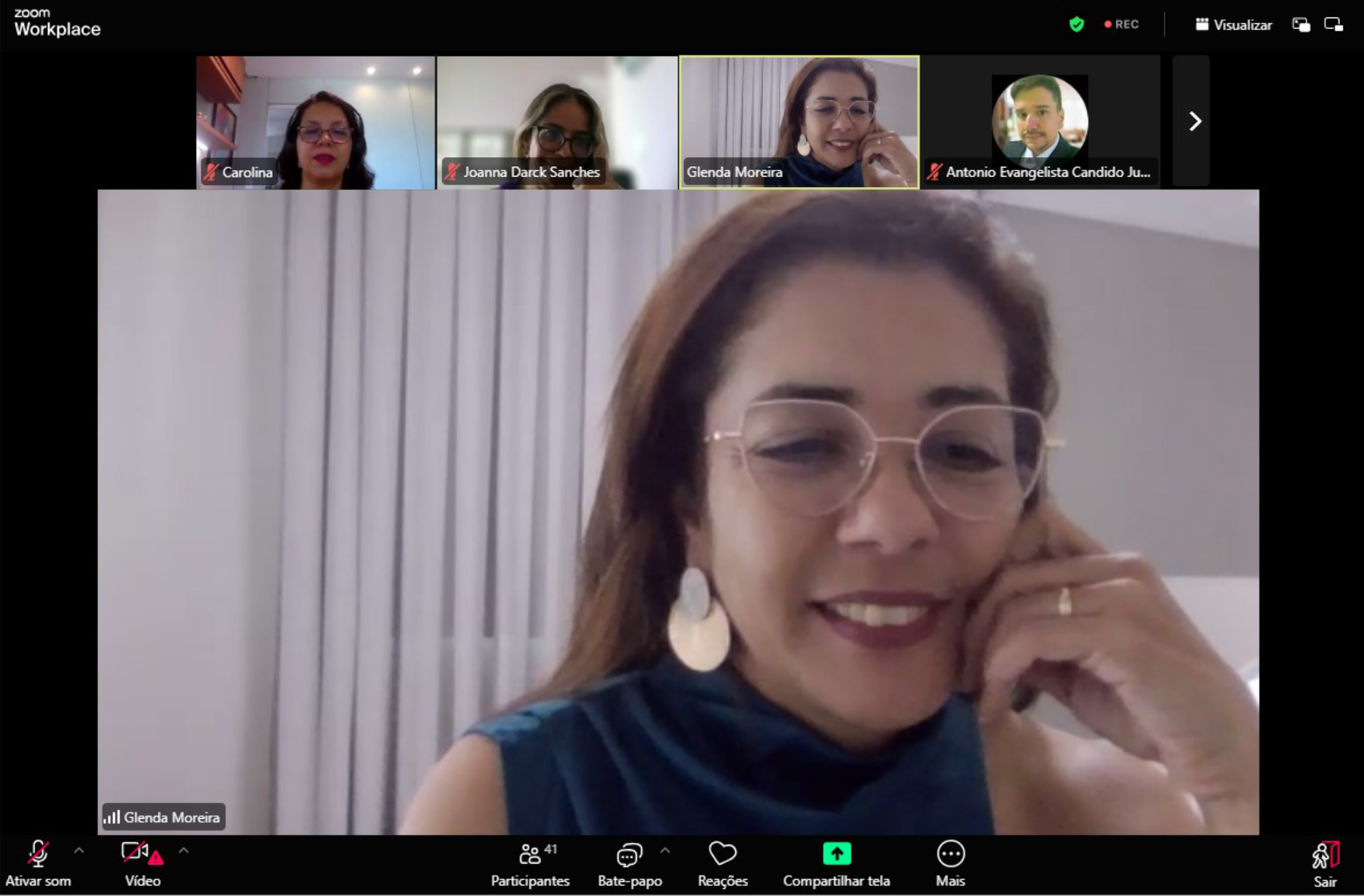 Foto de tela de computador mostrando videoconferência, com mulher clara de cabelos escuros (a palestrante) em destaque, ao centro. No topo, fotos de três mulheres e um homem como participantes.
