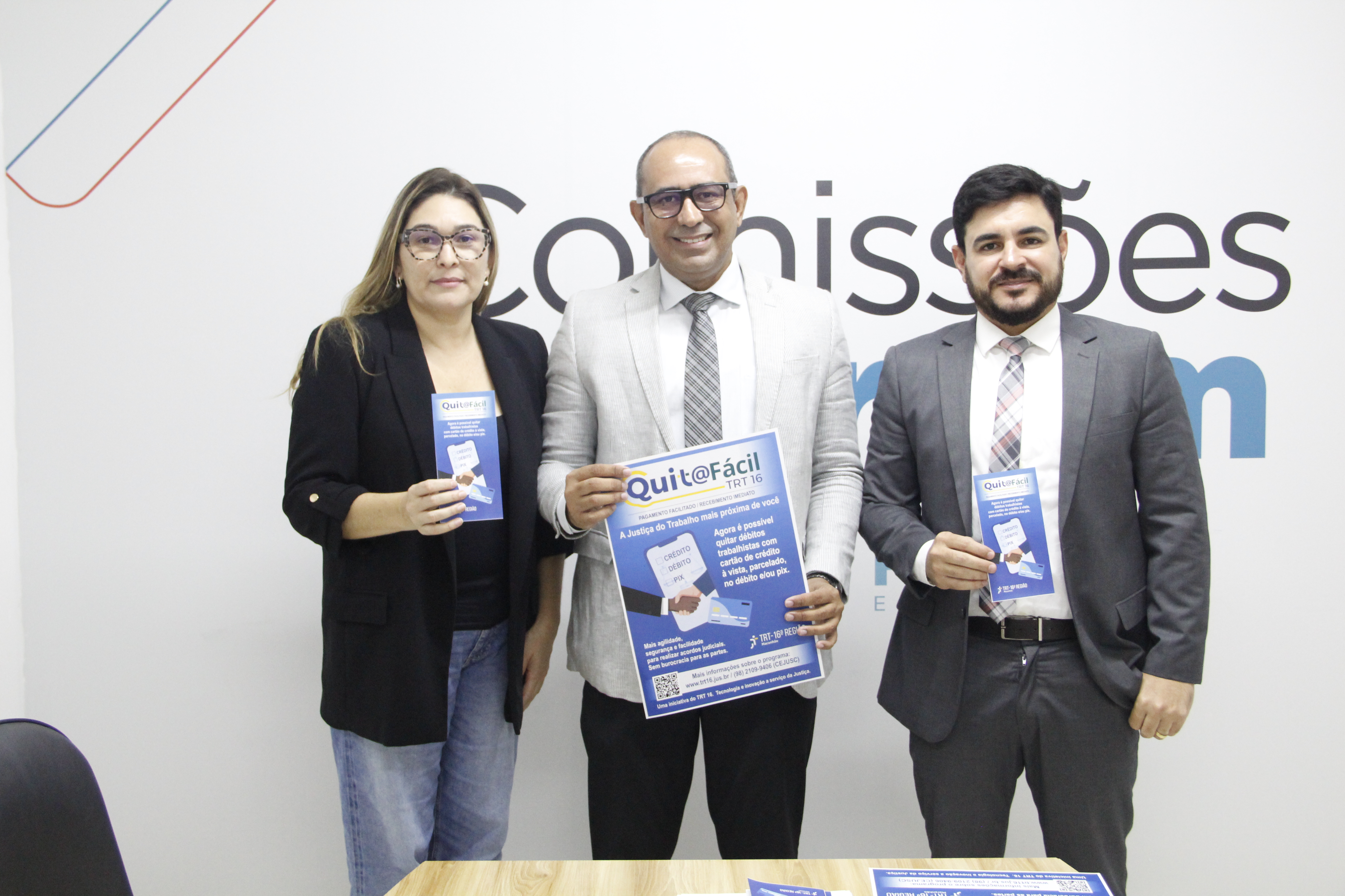 Foto mostra o secretário-geral da Presidência, George Adriano de Oliveira Costa, acompanhado da assessora administrativa da Diretoria-Geral, Lêda Raquel Araújo ao lado do presidente da Comissão de Direito Trabalhista da OAB/MA, Luiz Carlos Frazão. Eles estão em pé segurando o cartaz e o folder do programa Quita Facil