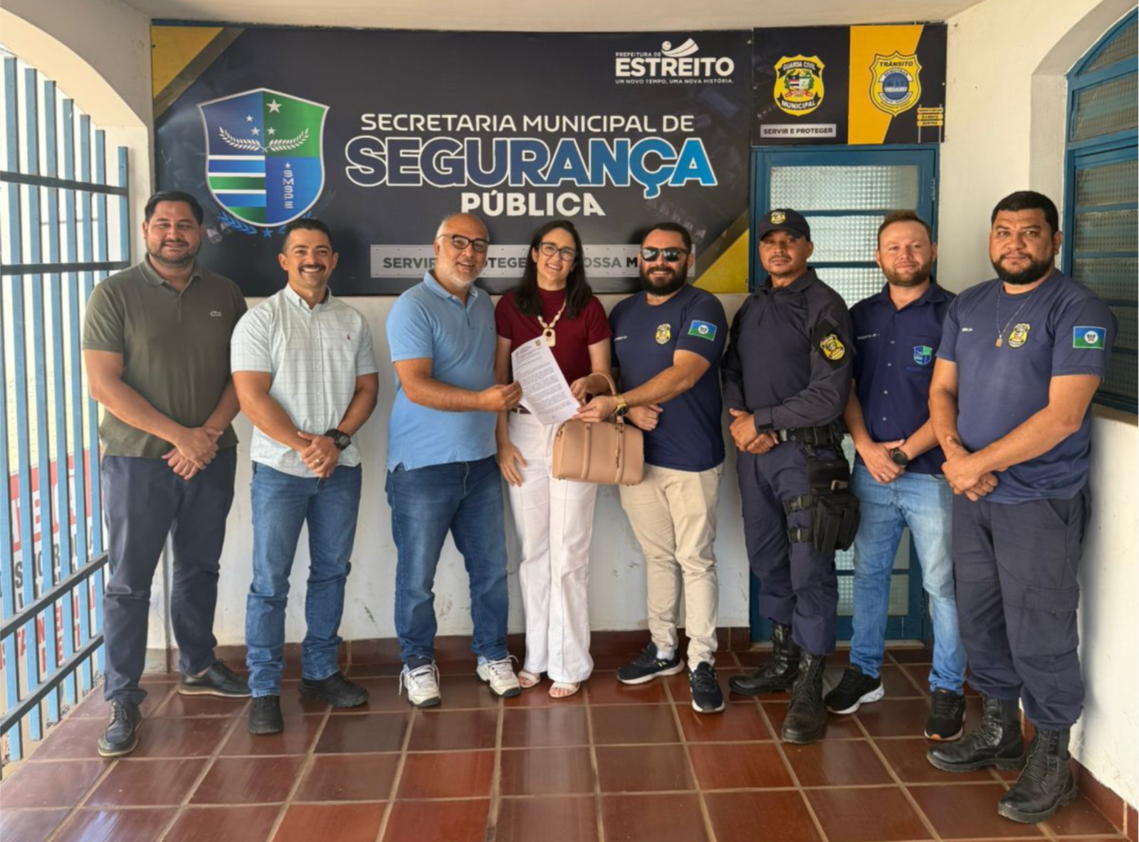 Foto mostra oito pessoas posicionadas em pé, sendo uma mulher. Ao fundo, um cartaz com o nome:  Secretaria Municipal de Segurança Pública da cidade de Estreito