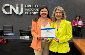 Foto mostra duas mulheres em pé, uma ao lado da outra. As duas seguram um certificado