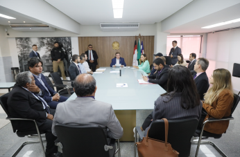 Foto mostra pessoas reunidades em volta de uma grande mesa de reunião.