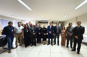 Foto mostra um grupo de pessoas em pé no meio de uma sala. 