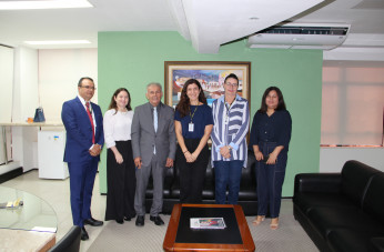 Foto mostra seis pessoas em pé. Uma ao lado da outra. Elas estão em uma sala de gabinete.