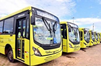 Foto mostra ônibus parados em uma garagem.