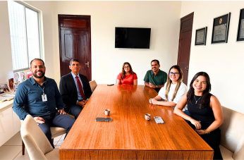 Foto mostra seis pessoas sentados à mesa. São 3 homens e três mulheres