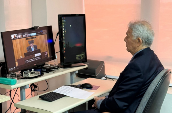 Foto mostra um homem usando terno, sentado em frente a um computador.