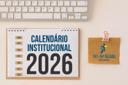 Arte com fundo cor de areia, tendo ao topo parte do teclado. Abaixo dele, um calendário de mesa com espiral, onde se lê CALENDÁRIO INSTITUCIONAL 2026. À direita, clipe rosado segurando uma folhinha de papel pardo, onde aparece a logomarca do TRT-16.
