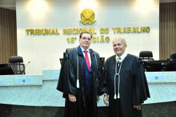 Foto de dois homens usando togas na cor preta. Ao fundo, em uma parede branca o nome TRIBUNAL REGIONAL DO TRABALHO - 16ª Região