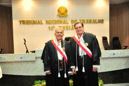 Foto mostra dois homens, em pé, ambos estão usando togas. Ao fundo o nome do Tribunal Regional do Trabalho da 16ª Região
