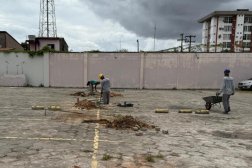 Foto mostra homens trabalhando em um pátio do estacionamento de veículos