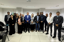 Foto mostra um grupo de pessoas, todos reunidos em um auditório