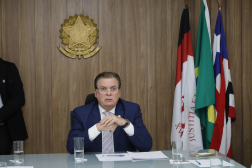 Foto mostra um homem sentado usando um terno azil