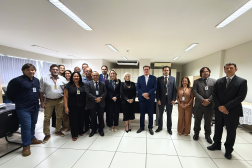 Foto mostra um grupo de pessoas em pé no meio de uma sala. 