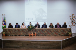 Foto de mesa de honra em evento com nove pessoas.