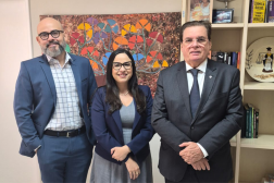 Foto de dois homens e uma mulher de pé e sorrindo.