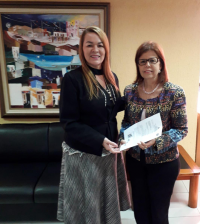 A presidenta Solange entregando à deputada Helena Duala a sugestão para o projeto de lei