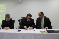 Desembargador Roberto Bacellar (E) e juiz Gustavo Castro observam o desembargador James Magno assinar o termo de cooperação