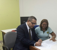 O presidente do TRT-MA assina o Termo de Doação, observado pela representante COOPRESL, Maria José de Castro