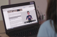 Imagem de mulher de costas ao computador vendo página acessível.