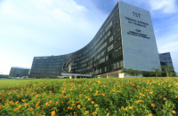 Foto do prédio-sede do Tribunal Superior do Trabalho e do Conselho Superior da Justiça do Trabalho, no primeiro plano o gramado e flores amarelas, e ao fundo o céu azul