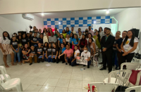 Imagem de muitos participantes juntos, alguns em pé e outros agachados posando para o registro fotográfico do evento.