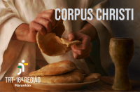 Foto representativa das mãos de Jesus partindo o pão acima de um prato com outros pães e com um cálice de madeira no canto inferior direito, sobre uma mesa. No topo, à direita, a inscrição Corpus Christi em letras brancas. No canto inferior esquerdo, a logo do TRT-16 na versão branca.