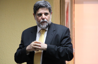 Ministro Caputo Bastos vestido com terno escuro e gravata amarela.