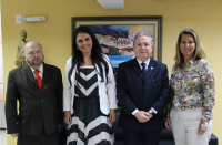 Foto posada de 2 homens e 2 mulheres à frente de parede amarela com quadro colorido.