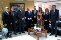 Desembargadoras e desembargadores ao lado do ministro Caputo Bastos. Todos estão de pé em sala de reunião, tendo ao fundo parede amarela e quadro colorido.