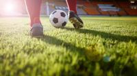 Atleta de futebol conduzindo a bola em um campo de futebol