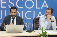 Juiz Sergei Becker ao lado do professor Ricardo Festi na mesa de abertura da Semana. O juiz veste terno escuro e o professor camisa de manga comprida azul. 