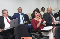 Participantes do curso sentados no auditório da Escola Judicial. Participando da aula, uma magistrada usa microfone.