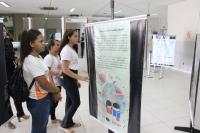 Grupo de estudantes em pé lendo informações sobre exploração do trabalho infantil em banner vertical.