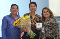 Foto de um homem e duas mulheres, uma delas segurando um buquê de flores.