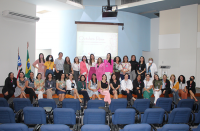 Foto de várias mulheres sentadas e em pé no palco de um auditório