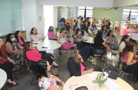 Mulheres sentadas em ambiente preparado para evento do Outubro Rosa