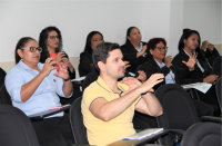 Foto de um homem e algumas mulheres usando a representação gestual-visual em Libras que significa comunicar