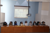 Foto de mulheres e homens sentados à mesa de honra do evento