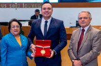 uma mulher e dois homens, um dos quais segurando uma medalha e 