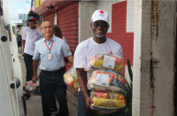 Dois homens carregando cestas de alimentos arrecadados.