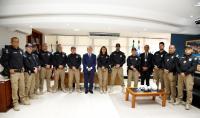 Grupo de vários homens e uma mulher, posando para a foto, posicionados em meia lua. Ao centro, uma mulher e um homem de terno azul, ladeados por outros homens uniformizados de policiais judiciais.