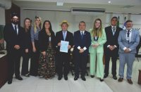 Grupo de pessoas posando para foto em uma sala. Todos estão em pé, lado a lado. 