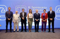 Grupo de sete pessoas em pé, posando para foto, sendo duas mulheres e cinco homens. Ao fundo, painel exibindo a arte do seminário de cor azul com detalhes branco.