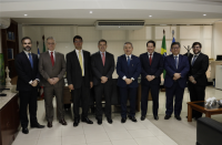 Grupo de oito pessoas posando para foto em pé, posicionados lado a lado, dentro de um gabinete. Todos estão vestidos formalmente com terno, gravata e calça social.