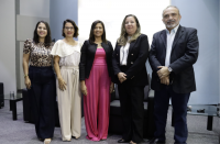 Cinco pessoas posando para foto, lado a lado, dentro de um auditório. Quatro mulheres do lado esquerdo e um homem.