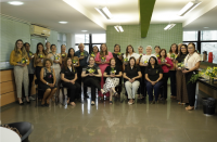 Foto de pessoas em pé e outras sentadas, segurando arranjos florais amarelos, sorrindo e posando para a foto.